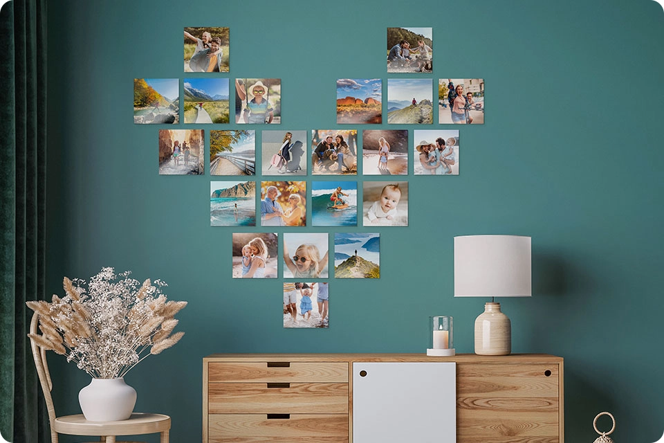 Multiple Snapfish Photo Tiles are displayed in the shape of a heart on a green wall above a dresser with a lamp on top