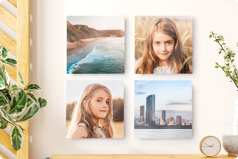A set of four Snapfish Photo Tiles featuring family and vacation photos is displayed on a wall with a hat and plant nearby