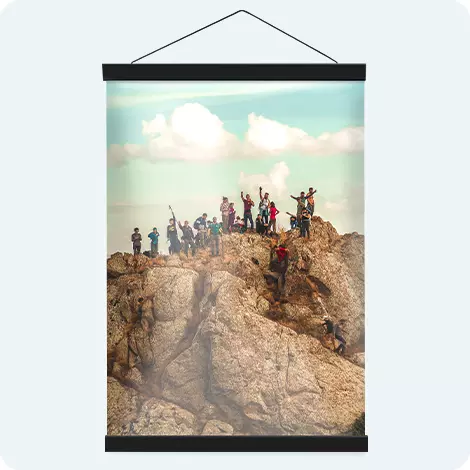 Hanging photo poster showing a group of tourists on top of a rocky landscape. 